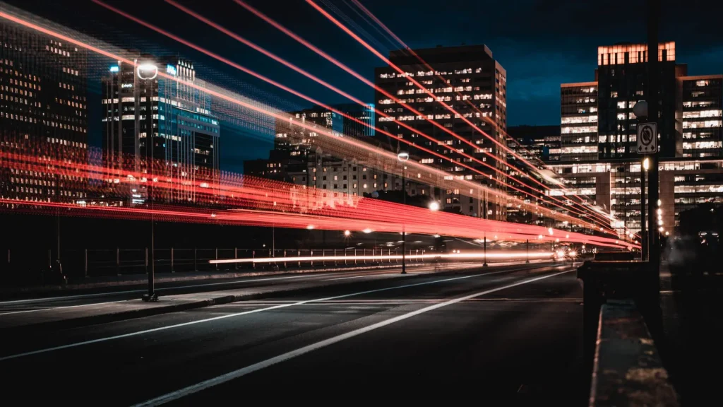 Long exposure shot of cars driving through a city at night. The car lights are streaking across the photo.