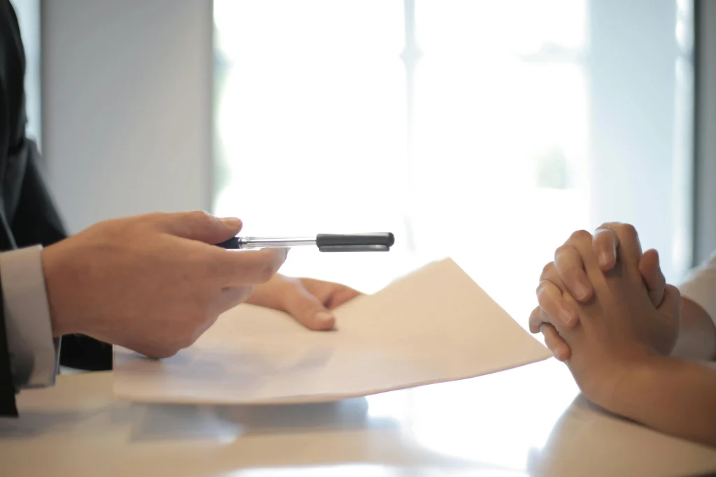 Hand passing paper and pen to interviewee