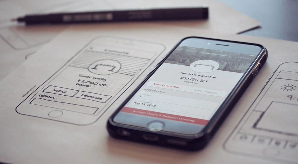 Responsive website on a mobile phone shown sitting on top of hand-drawn wireframes of the same website.